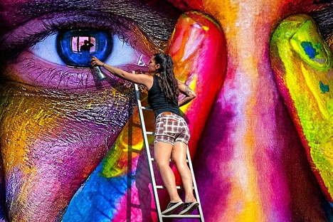 Merdiven üzerinde renkli insan yüzü ve insan gözü boyayan kadın