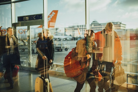 Havalimanında çanta ve valizleriyle birlikte uçağa doğru yürüyen yolcular
