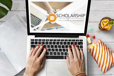 Online burs başvurusu gerçekleştiren bir öğrenci, burs başvuru ekranının görüntüsü ve çalışma masasındaki renkli eşyalar