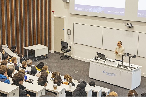 Queen Mary University of London kampüsündeki amfide ders anlatan bir akademisyen ve dersi dinleyen öğrenciler
